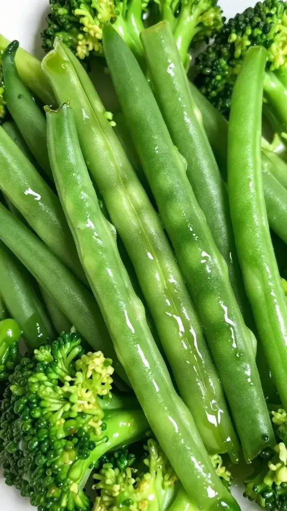 closeup of vibrant green beans and broccoli tossed in shimmering glaze