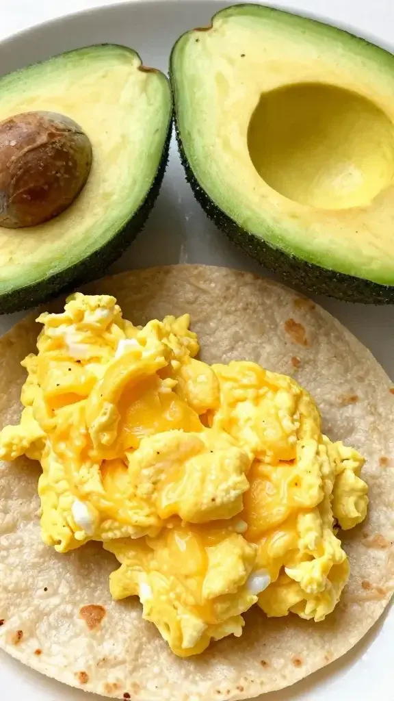 Closeup avocado halves with sunny scrambled eggs on tortilla