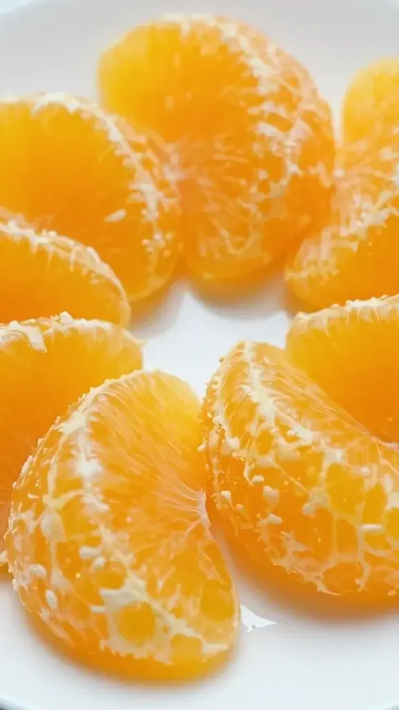 Closeup of orange segments on white plate, vibrant texture