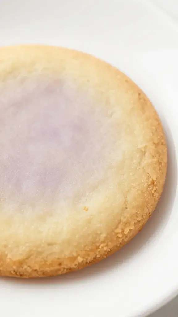 Closeup of pale lemon lavender cookie on white plate, crisp edge visible