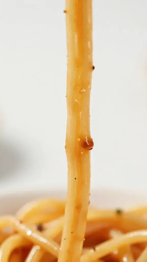 closeup of single spaghetti strand coated in sauce with lobster