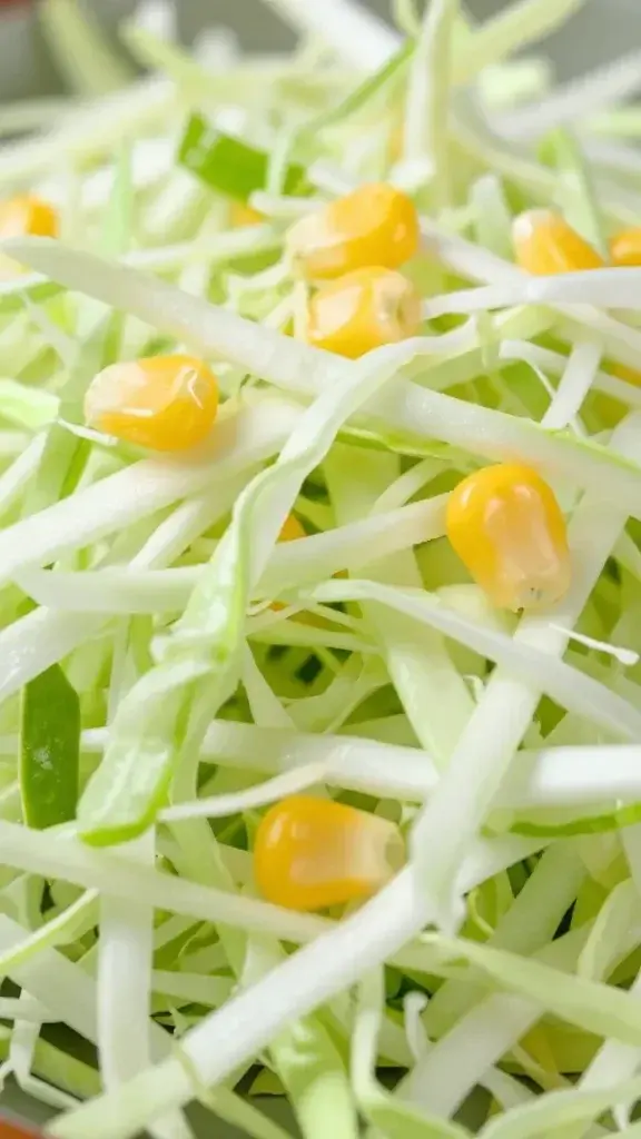 Closeup of shredded cabbage with lime and corn kernels