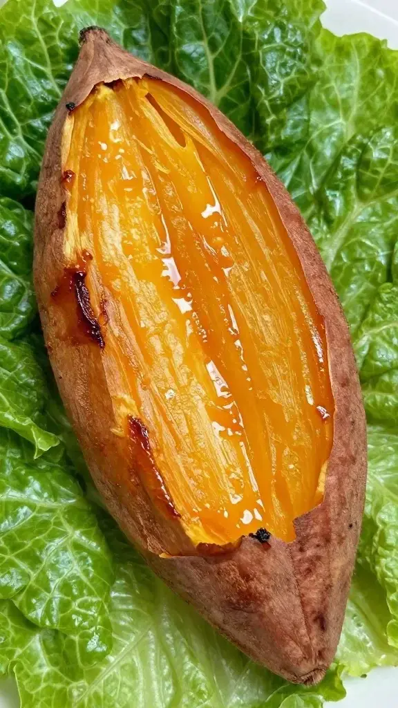 closeup of roasted sweet potato half with caramelized edges on greens