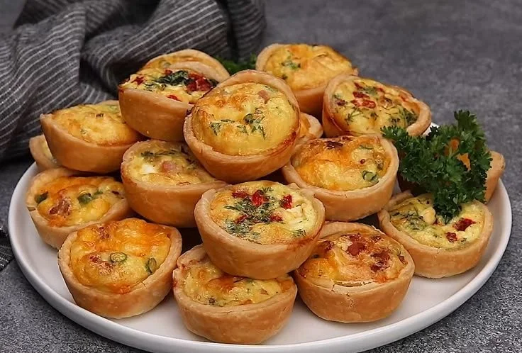 Variety of tasty mini quiches served on a platter.